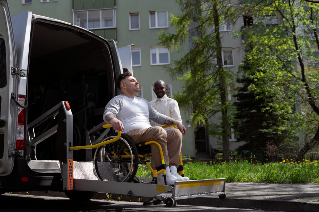 Caregiver helping a wheelchair user onto a van's accessible lift